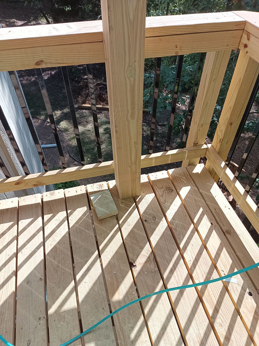 A wooden deck with a metal railing and a blue rope.