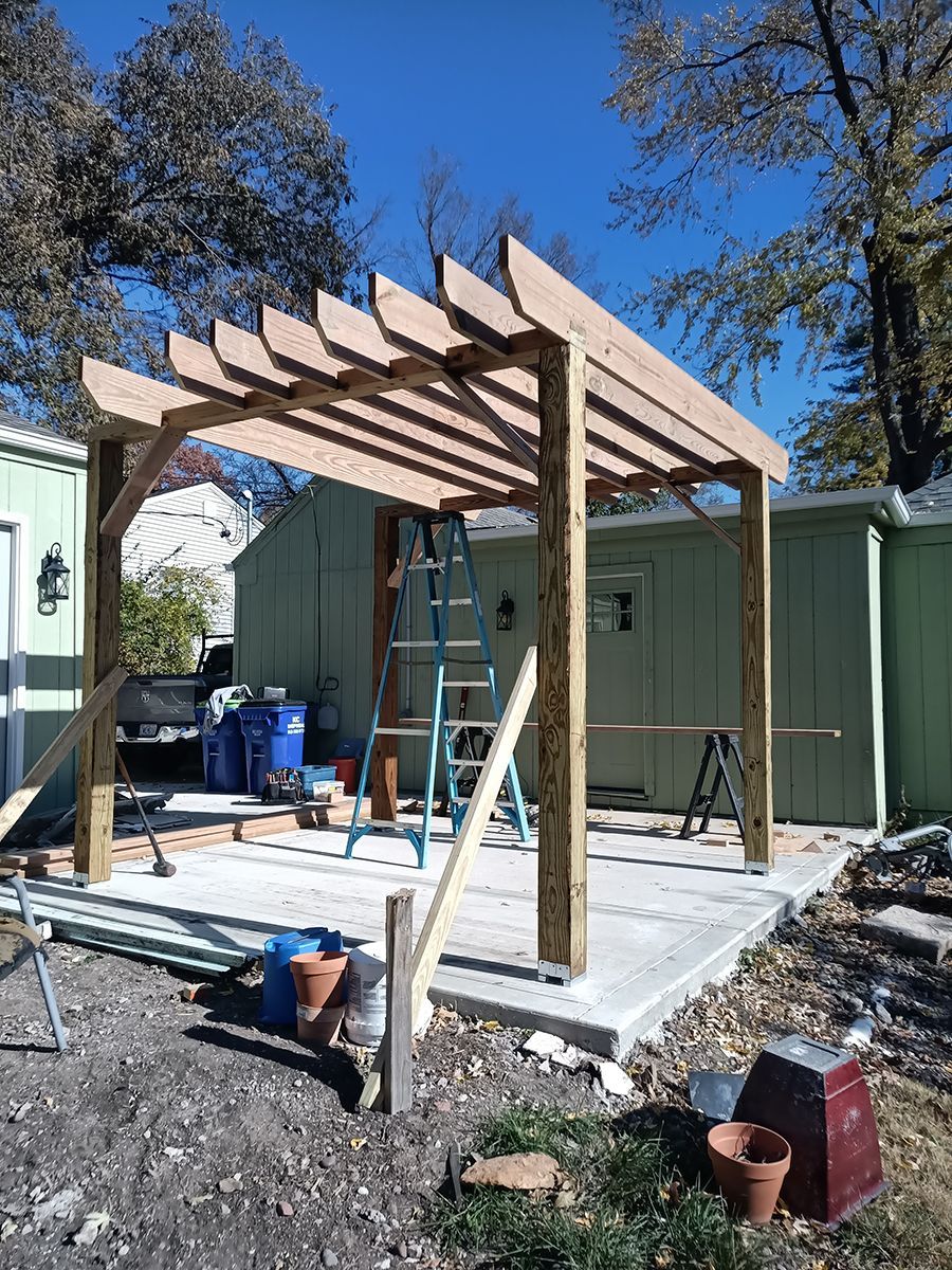 A wooden pergola is being built in the backyard of a house.
