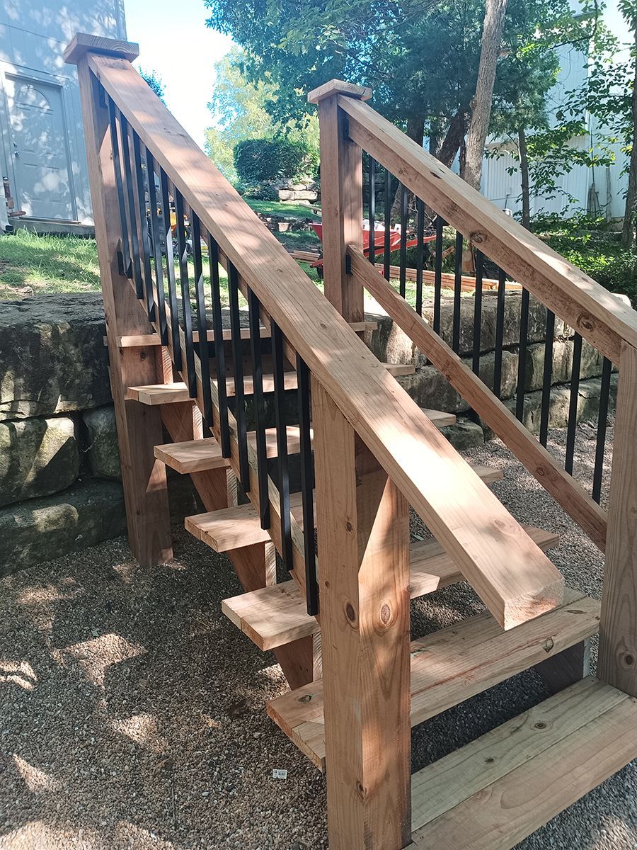 A wooden deck with stairs and a metal railing.