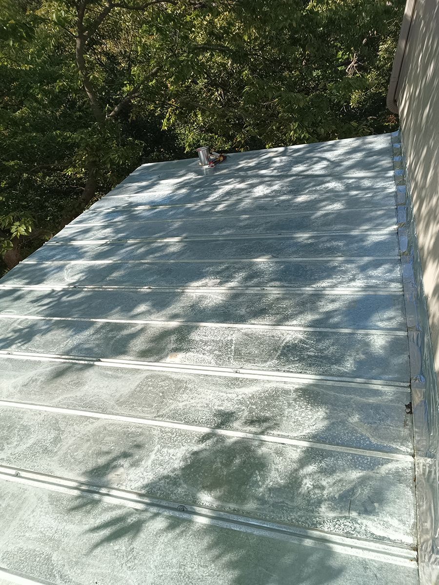 A close up of a roof with trees in the background.