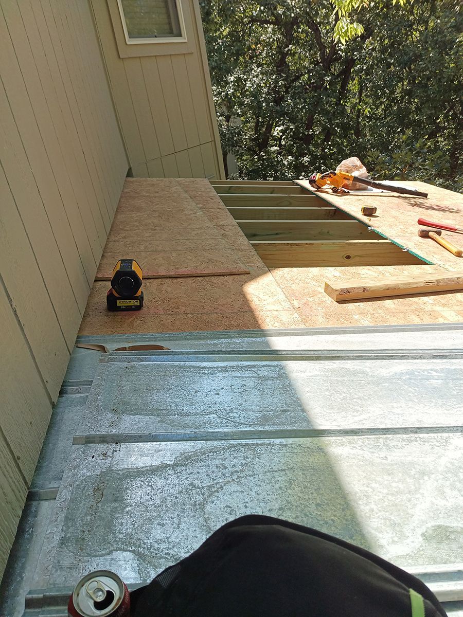 A person is sitting on a roof with a can of soda next to them.