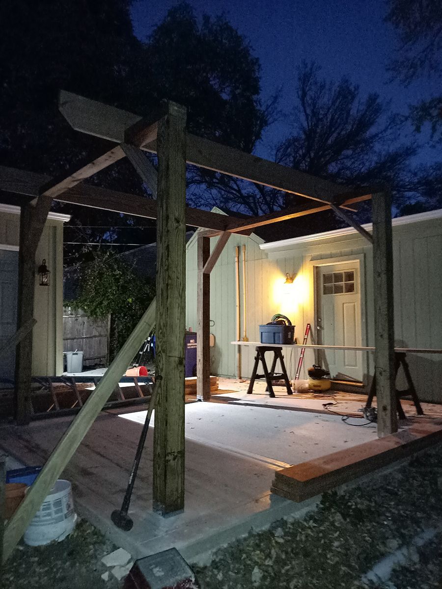 A wooden structure is being built in front of a house at night.
