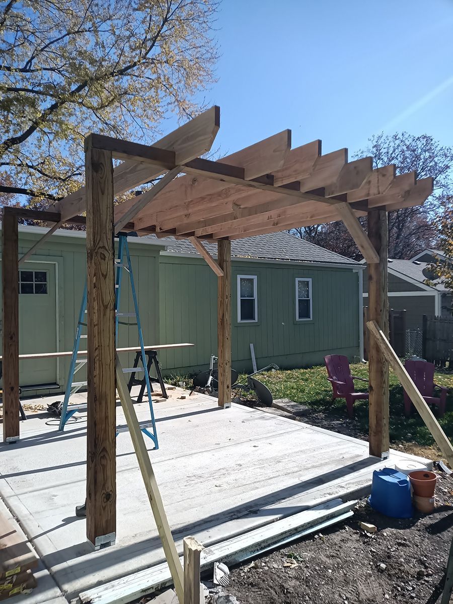 A wooden pergola is being built in the backyard of a house.