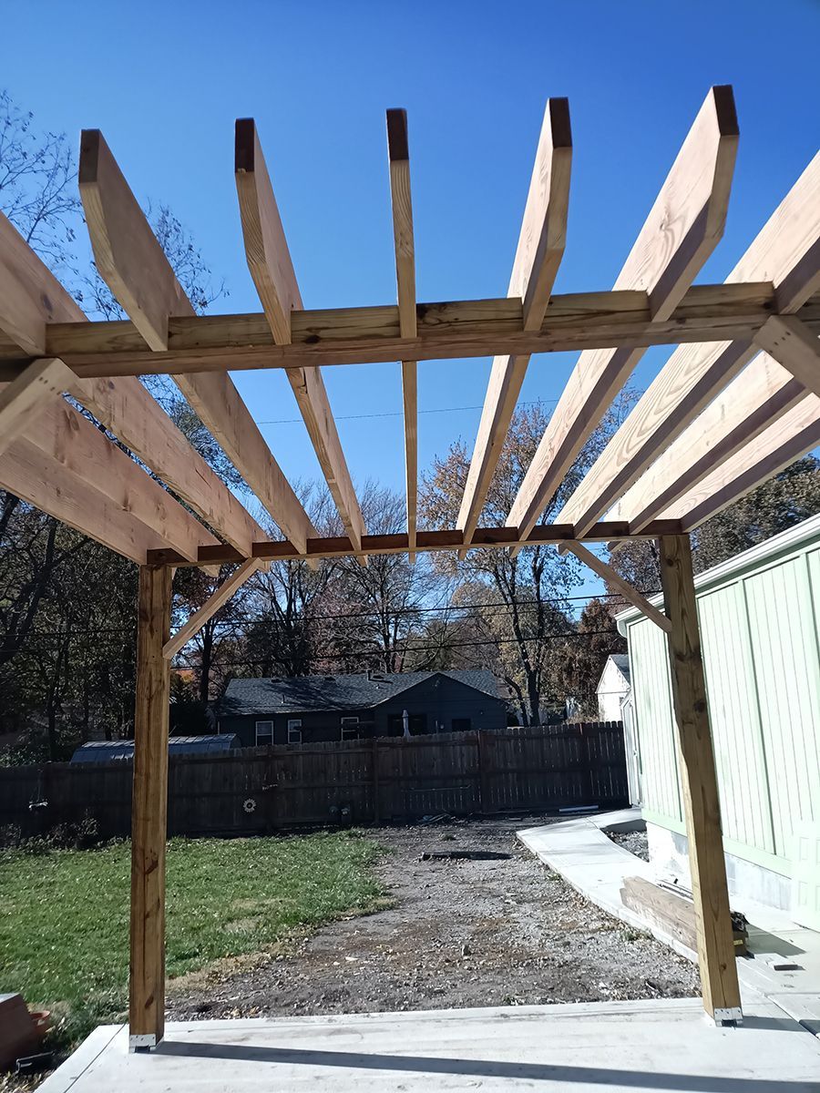 A wooden pergola is being built in a backyard.