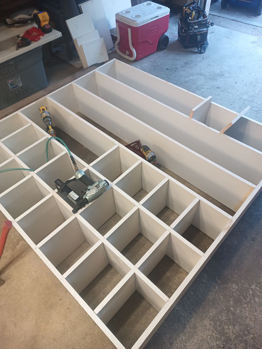 A large white shelf is being built in a garage.