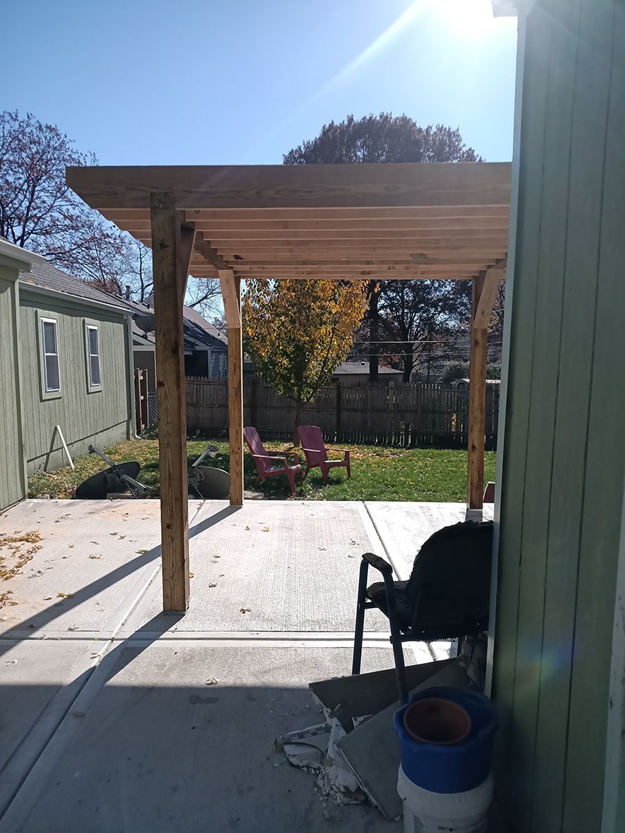 A wooden pergola is sitting in the backyard of a house.