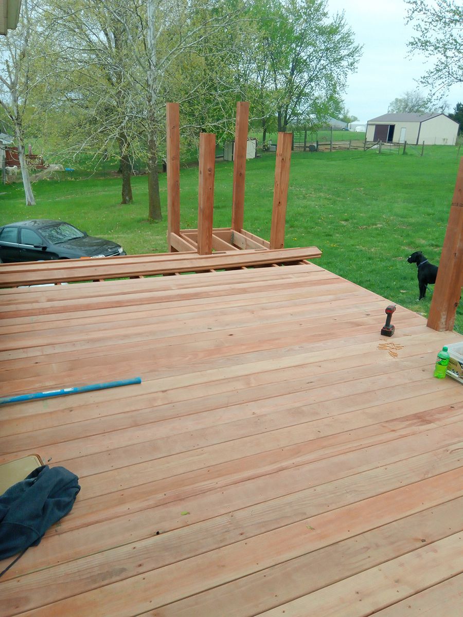 A wooden deck is being built with a dog in the background.