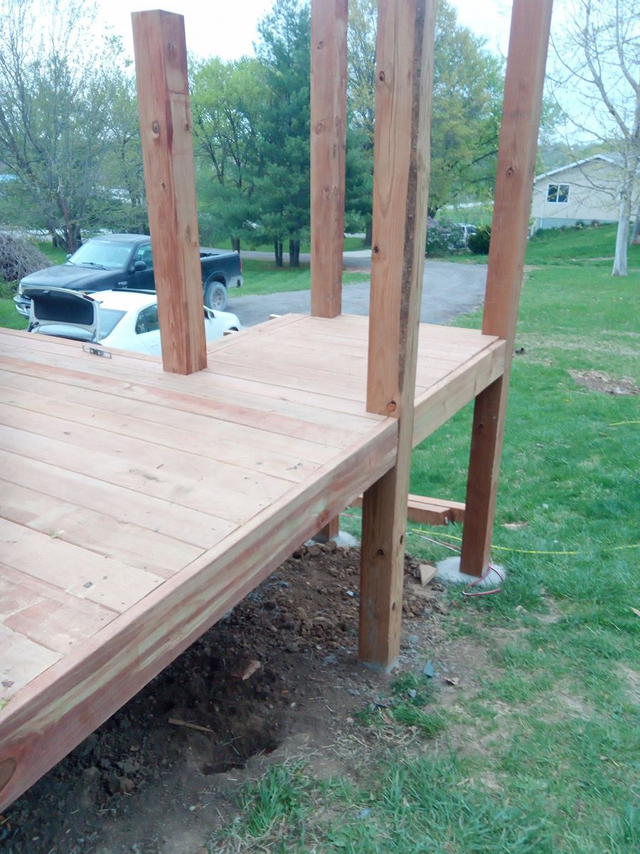 A wooden deck is being built in a yard with a truck parked in the background.