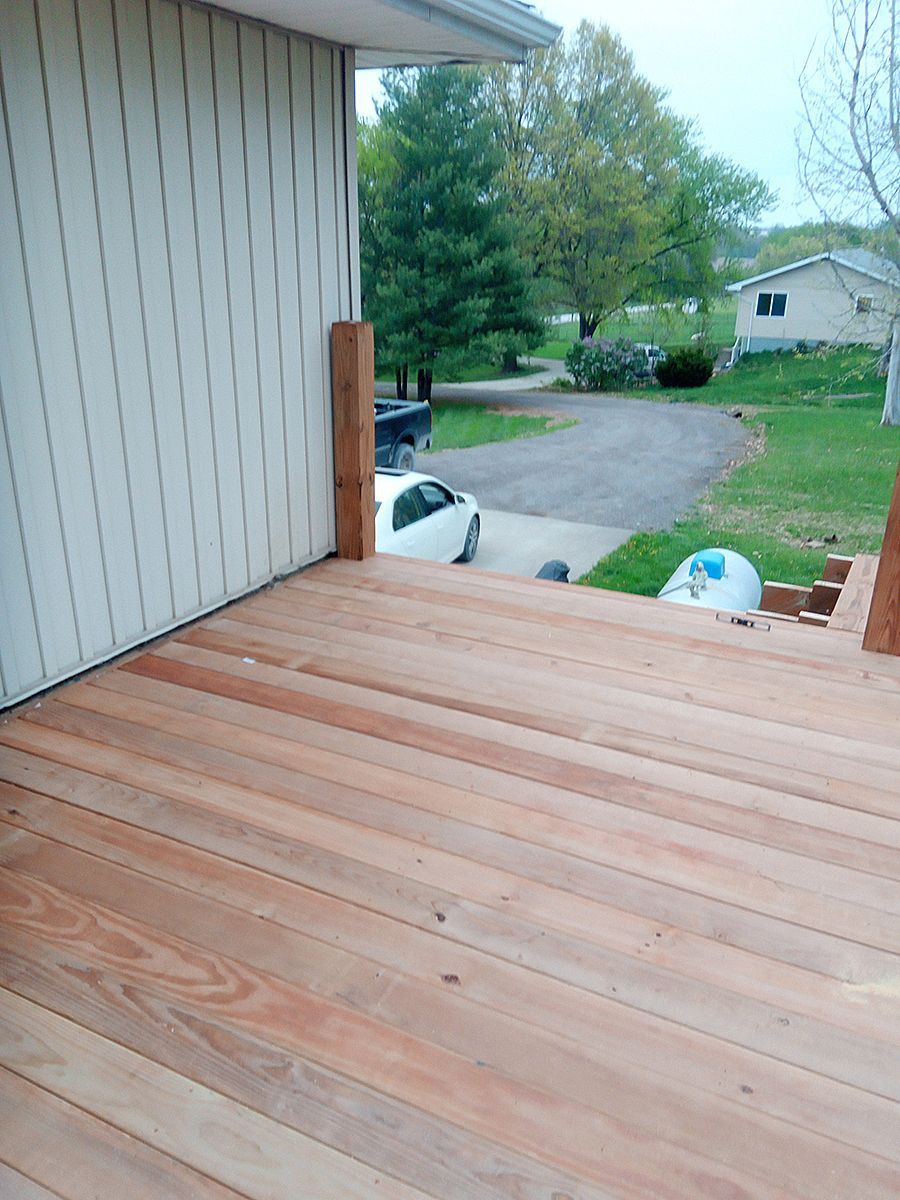 A wooden deck with stairs leading up to a house.