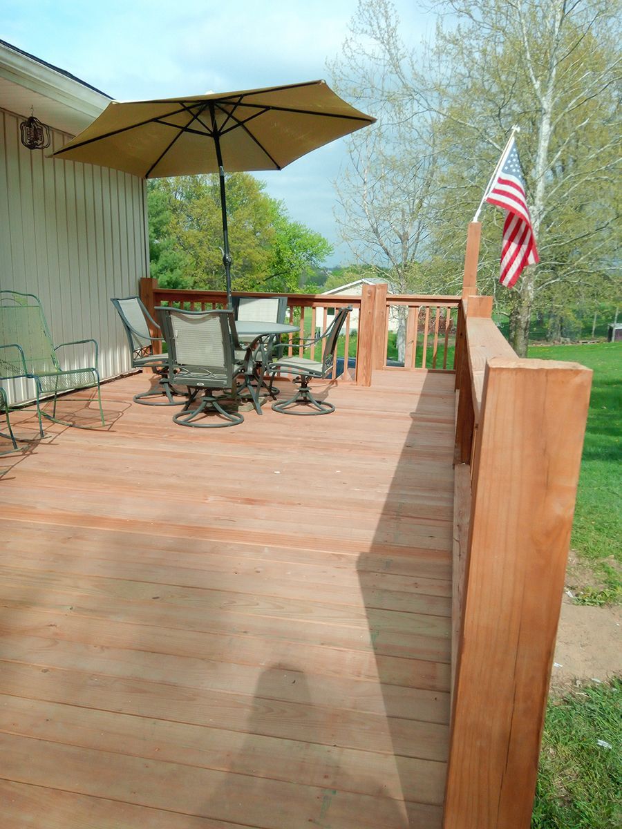 A wooden deck with a table and chairs and an umbrella.