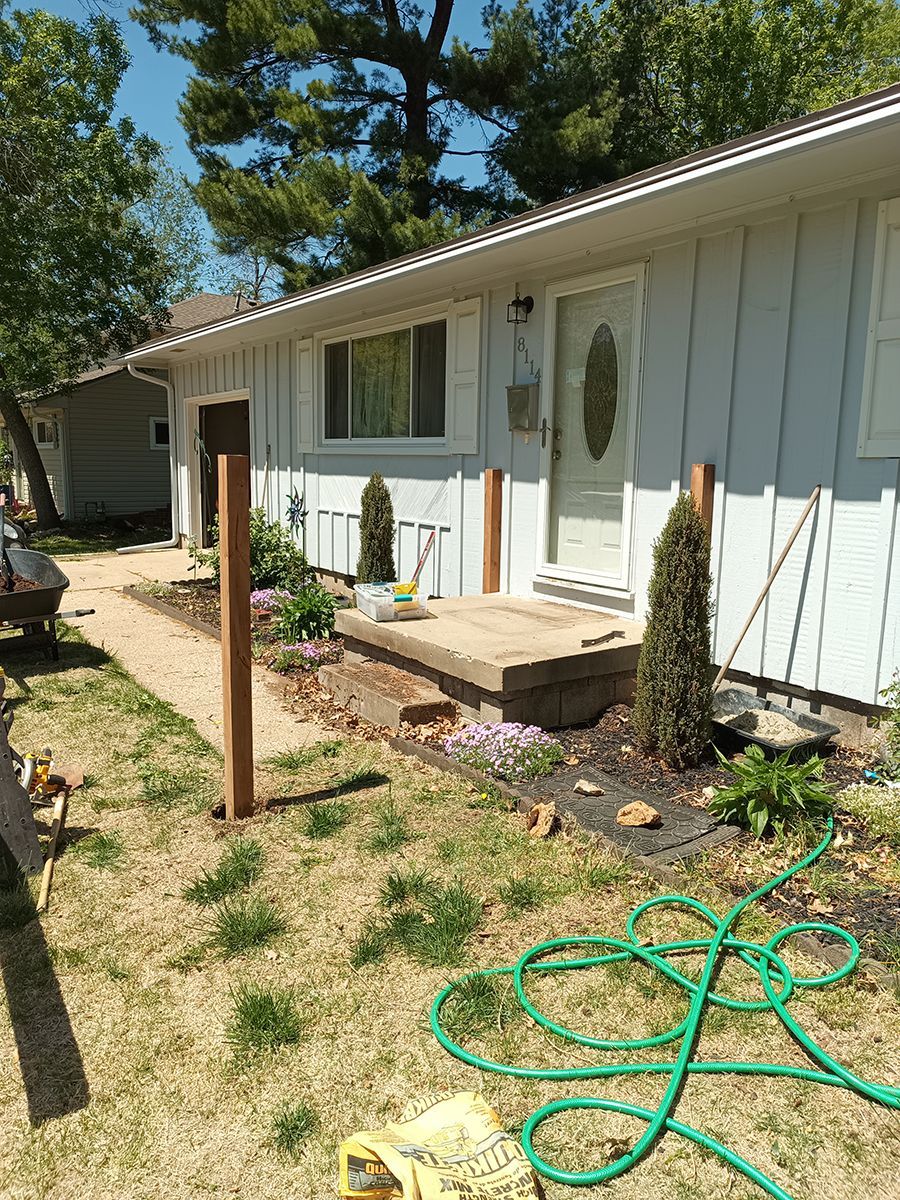 A white house with a green hose in front of it.