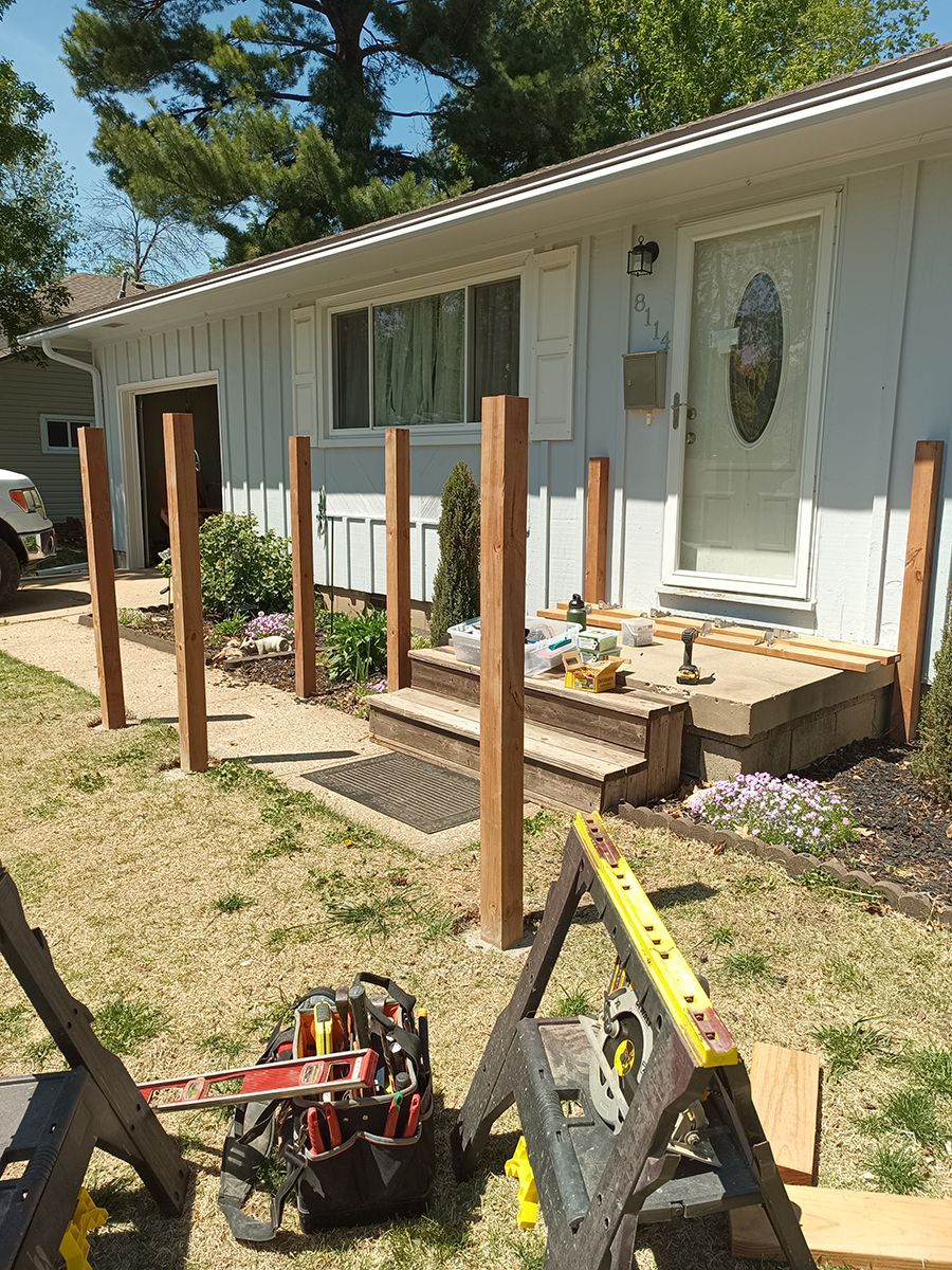 A wooden fence is being built in front of a white house.