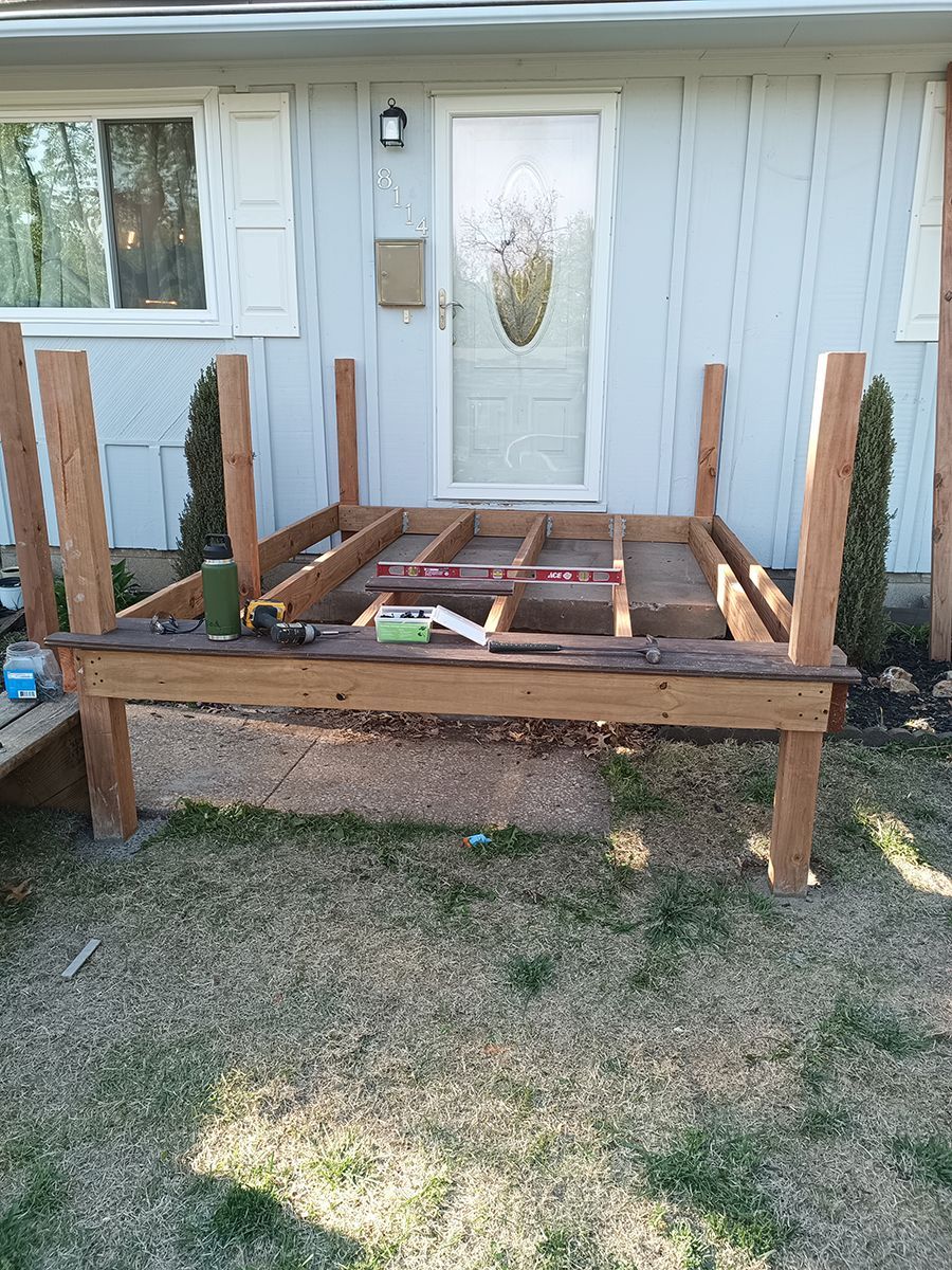 A wooden deck is being built in front of a house.