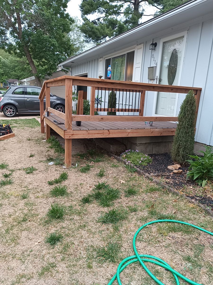 A house with a wooden deck and a green hose in front of it.