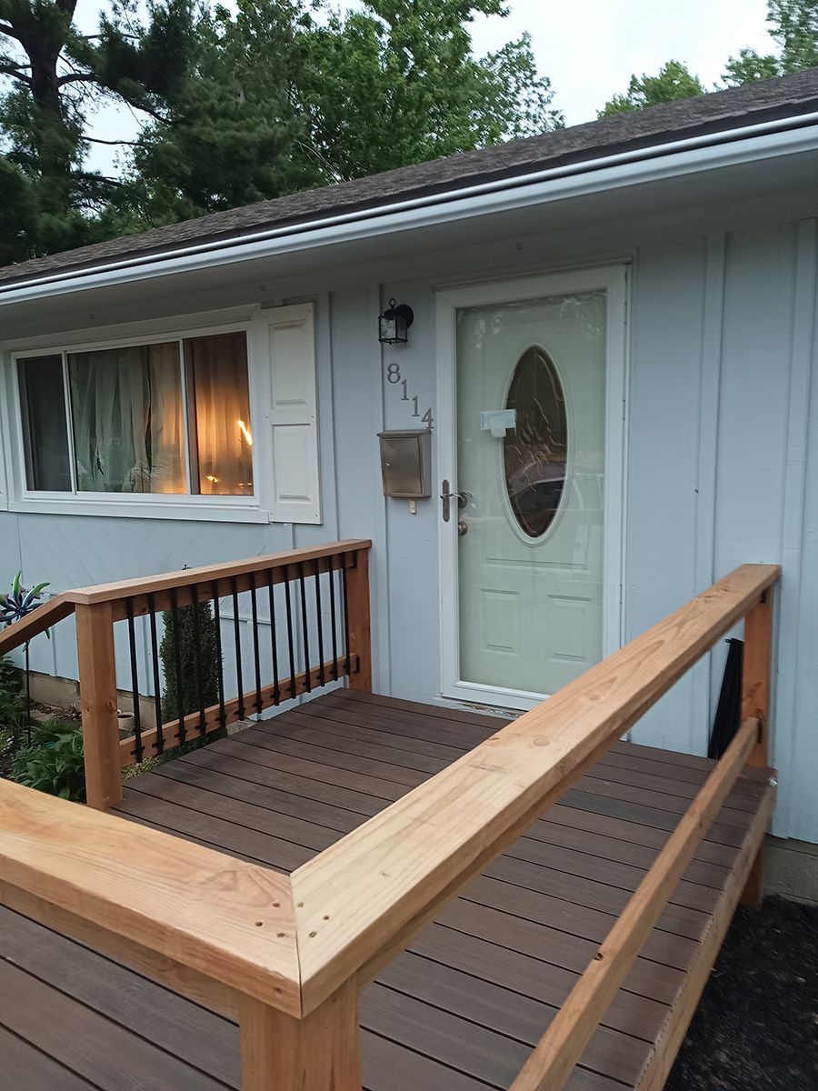 A house with a wooden deck and stairs leading to the front door.