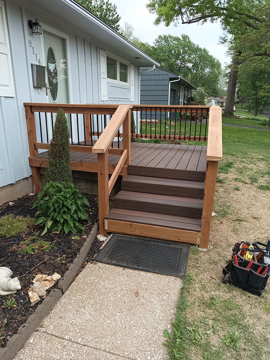 A wooden deck with stairs leading up to it is in front of a house.