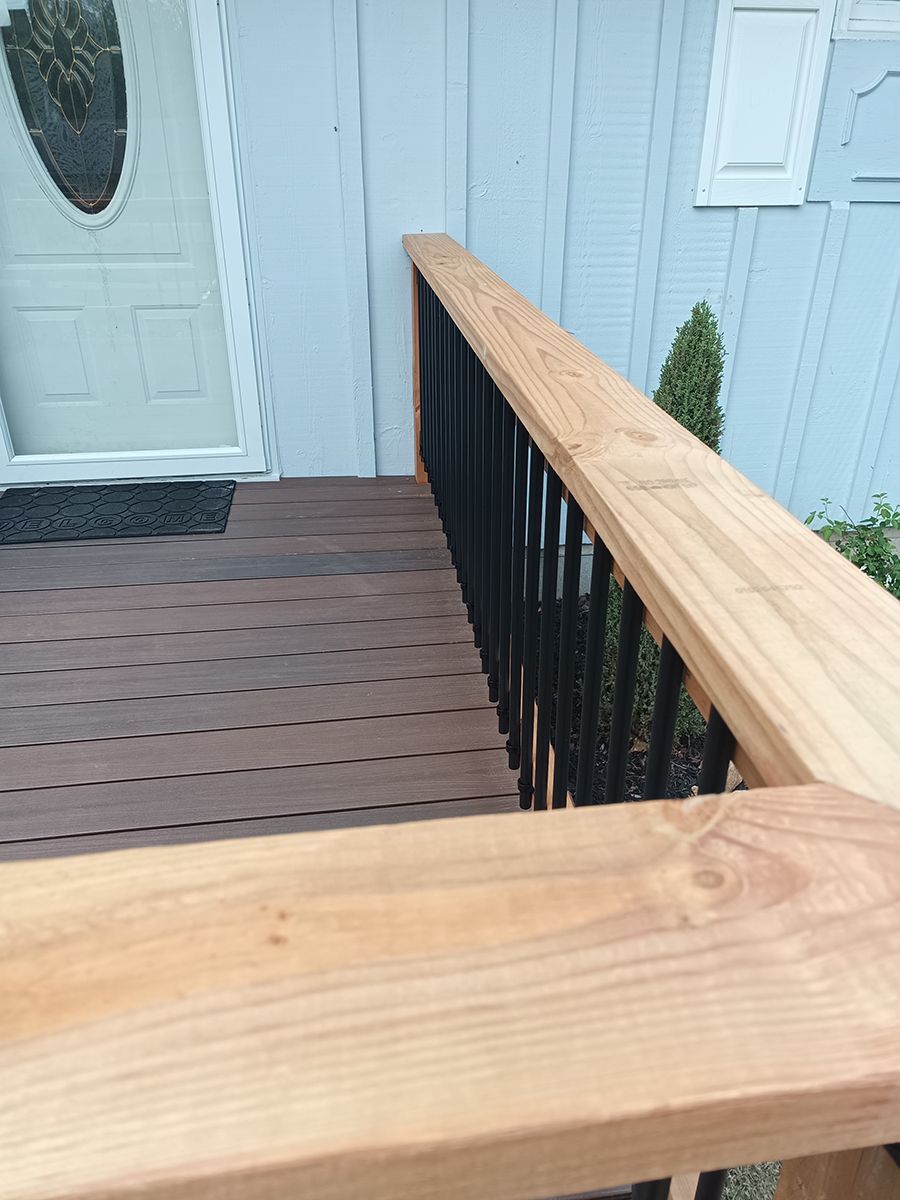 A wooden deck with stairs leading up to the front door of a house.