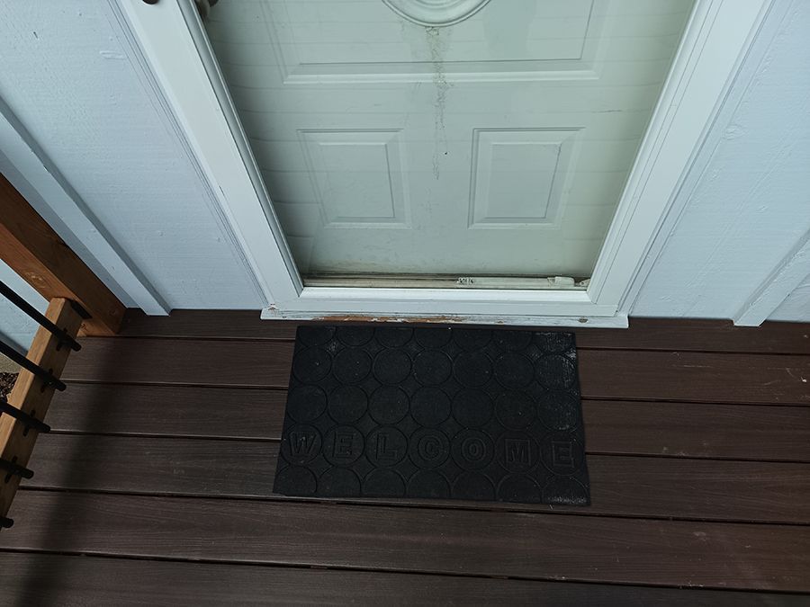 A door with a doormat on the floor in front of it.