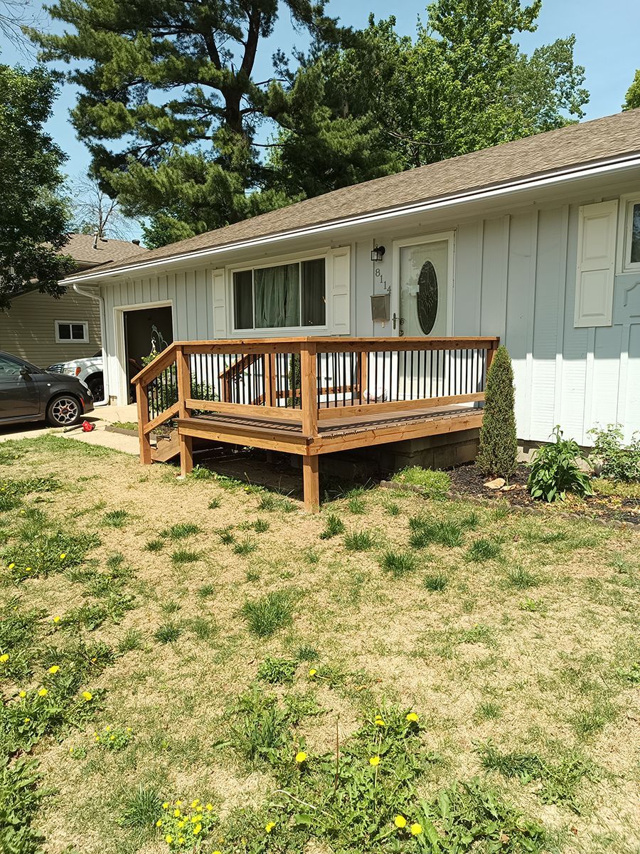 A white house with a wooden deck in front of it.