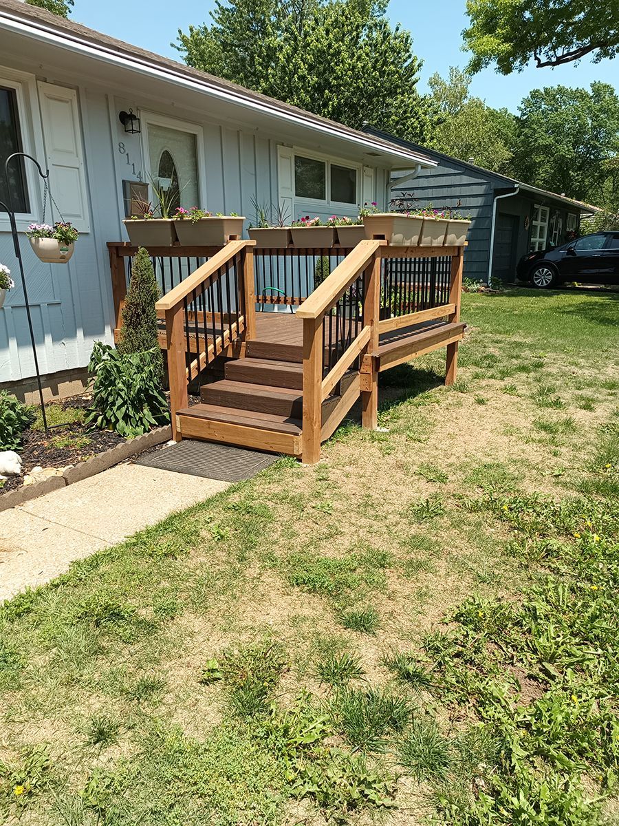 A wooden deck with stairs leading up to it is in front of a house.