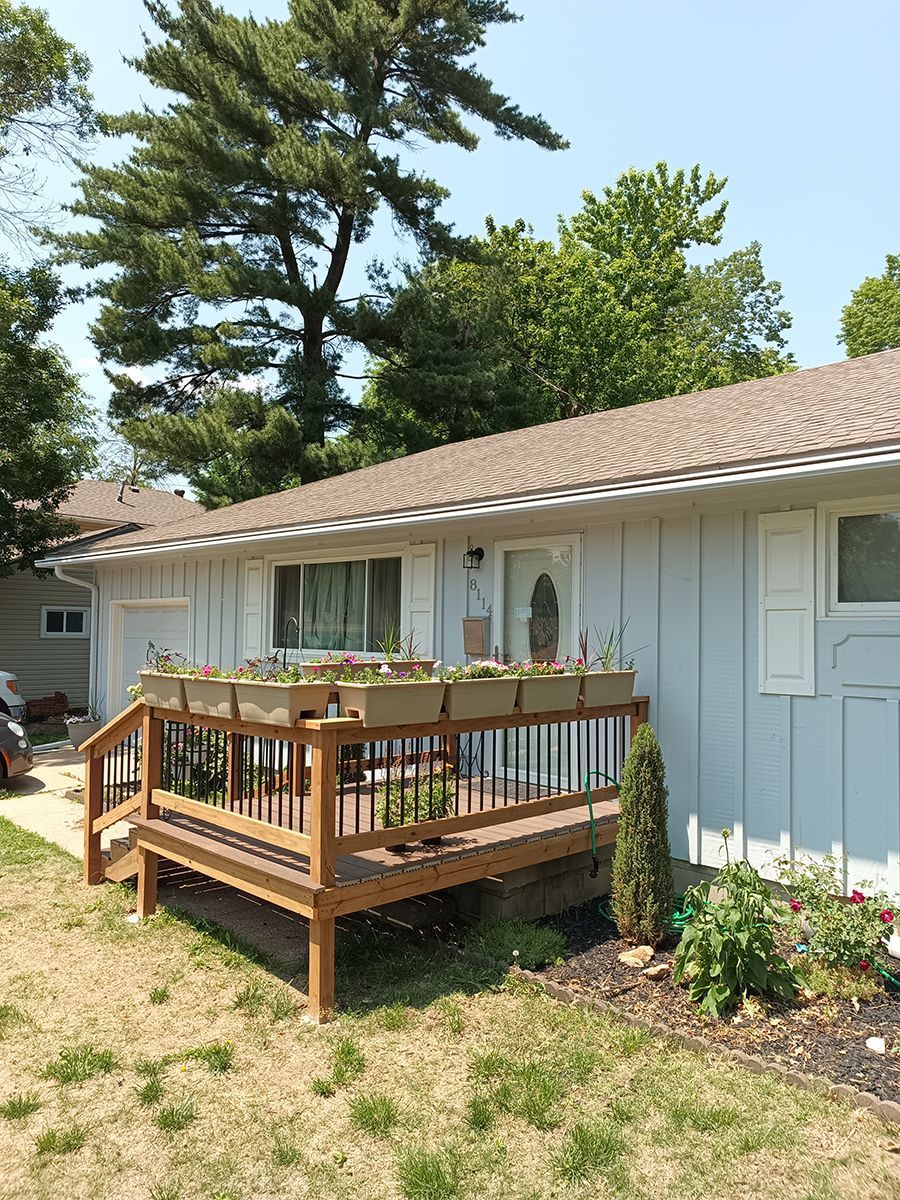 A white house with a wooden deck and planters on it.