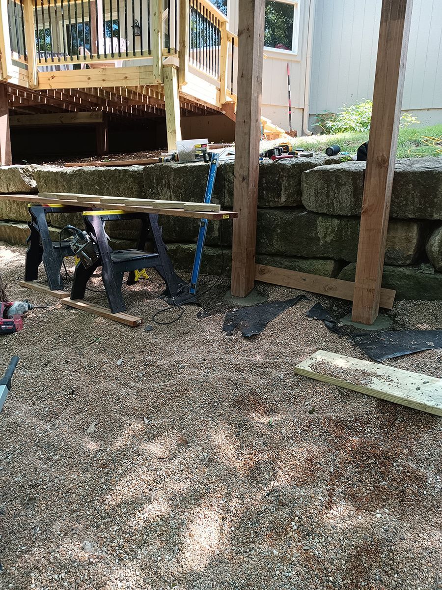 A person is working on a wooden deck in a backyard.