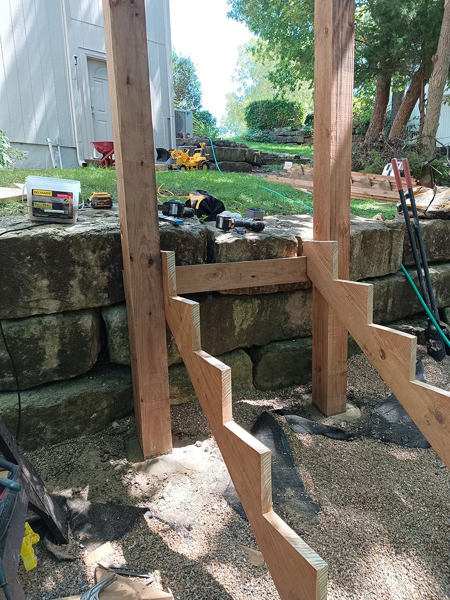 A wooden staircase is being built next to a stone wall.
