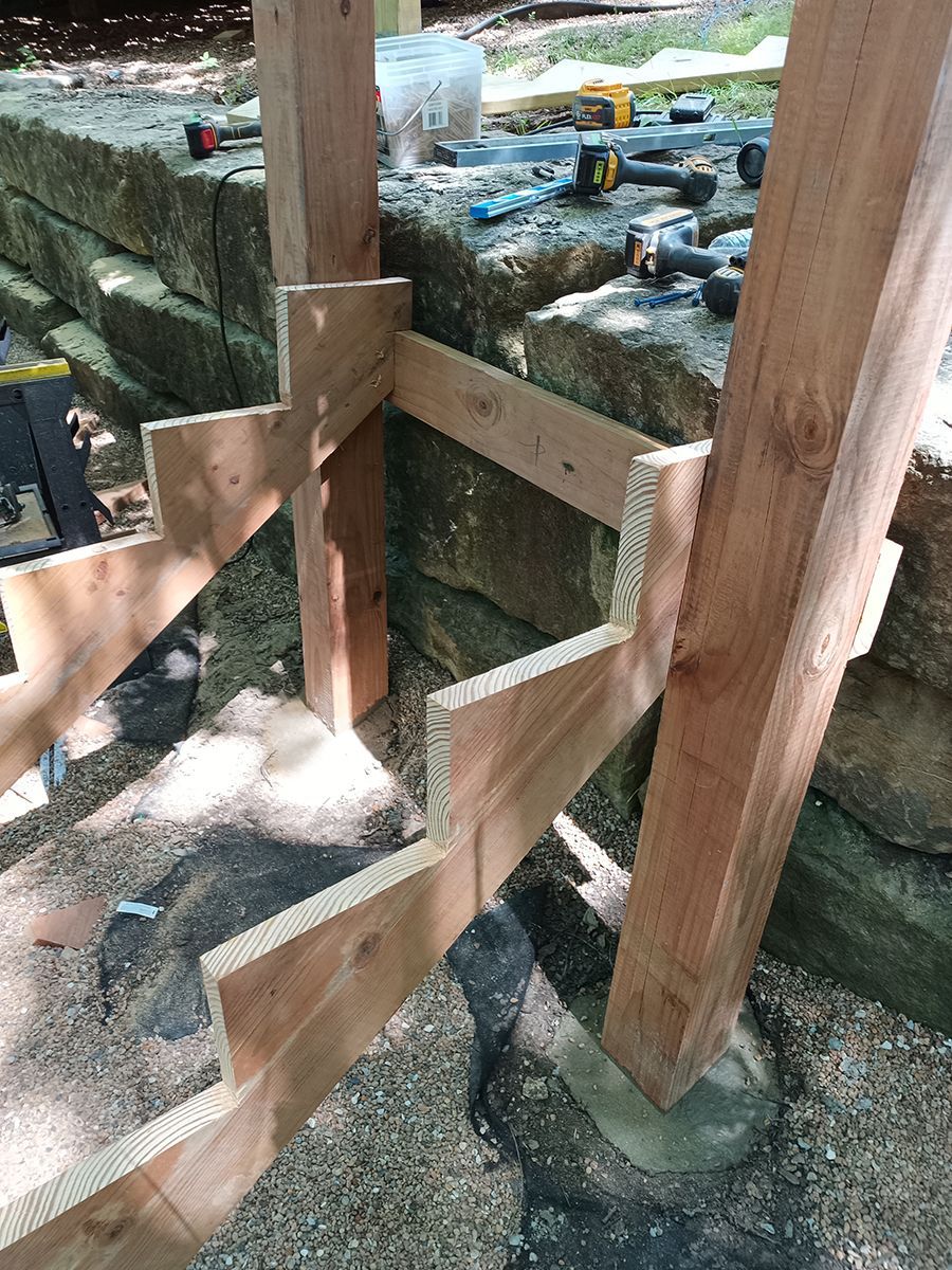 A wooden staircase is being built next to a stone wall.