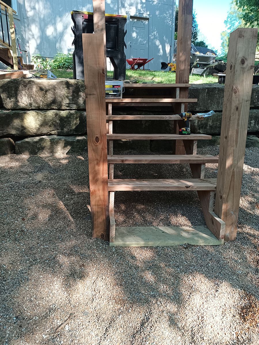 A wooden staircase is sitting on top of a pile of gravel.
