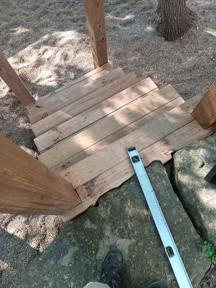 A person is measuring a wooden deck with a level.