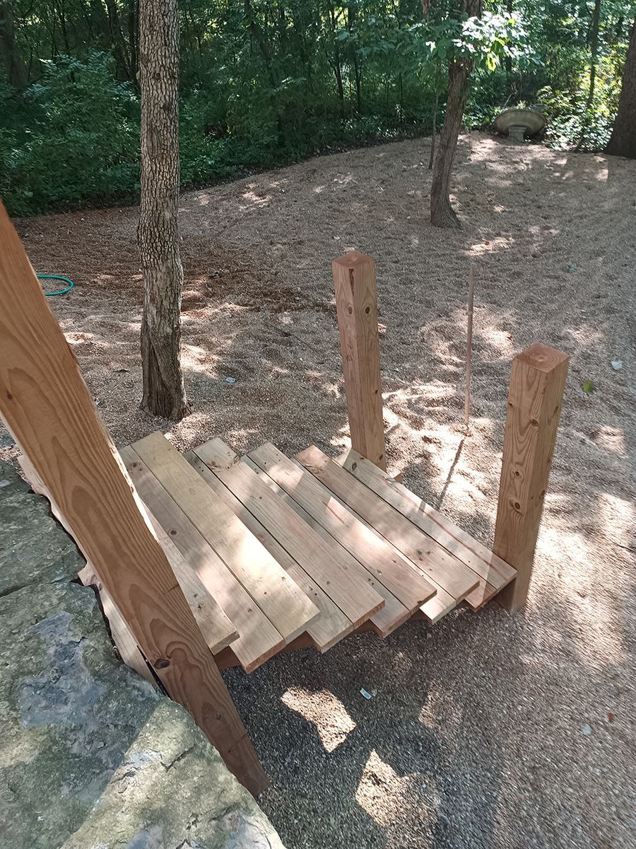 A wooden bridge is sitting in the middle of a forest.