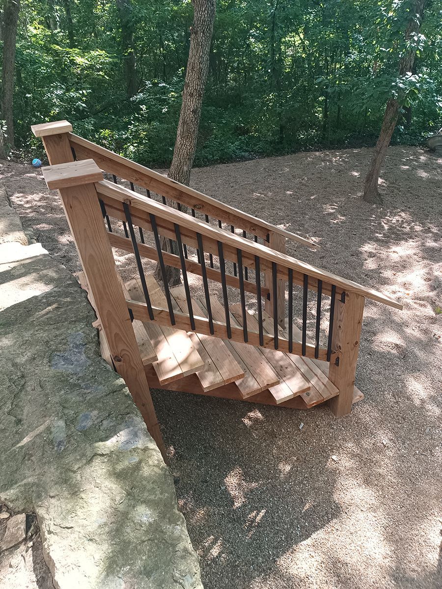 A wooden staircase with a metal railing in the woods.