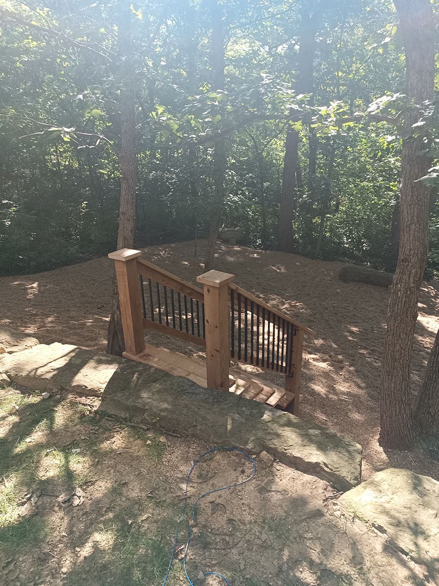 A wooden bridge in the middle of a forest surrounded by trees.
