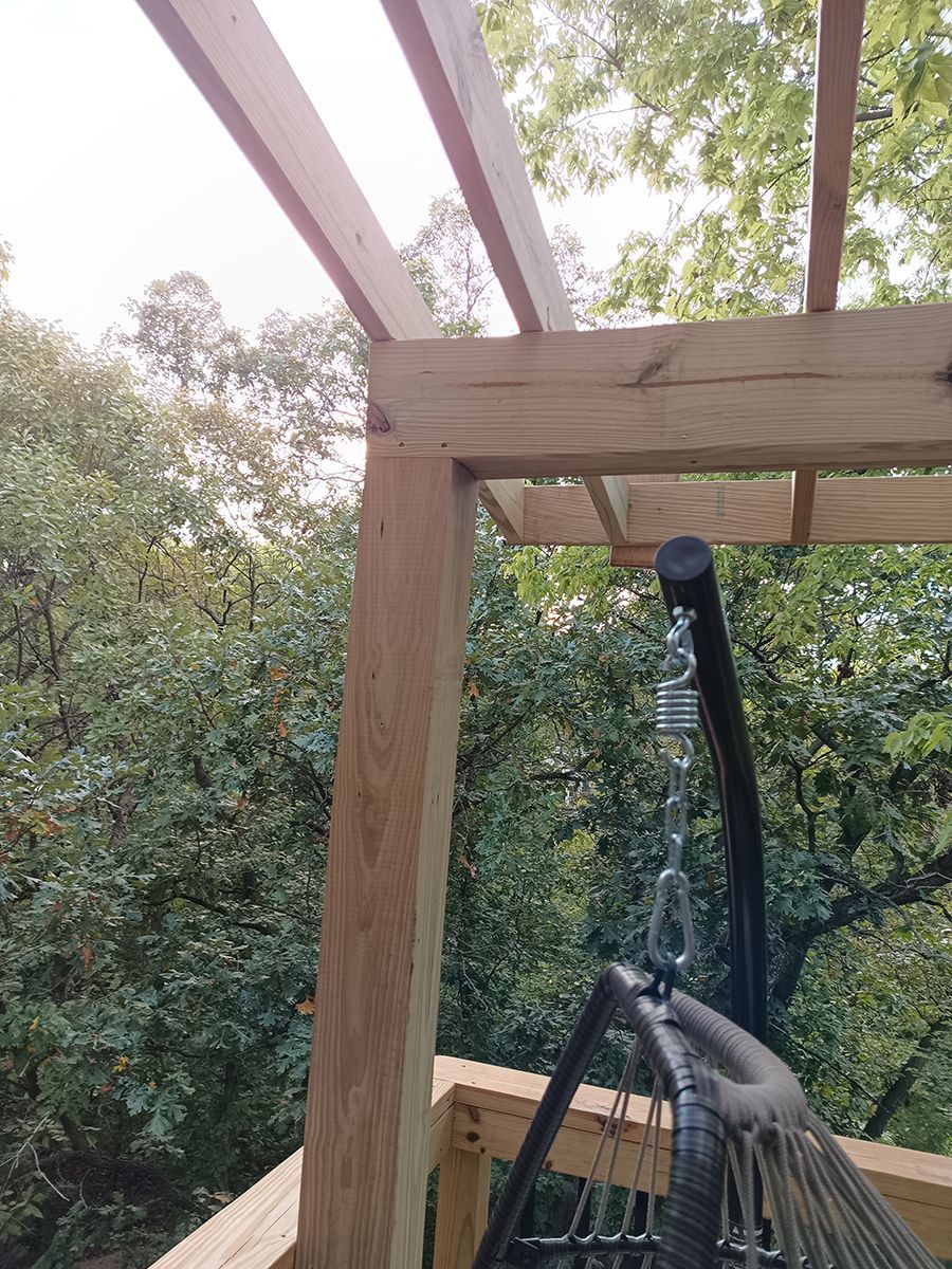 A hammock is hanging from a wooden structure on a deck.