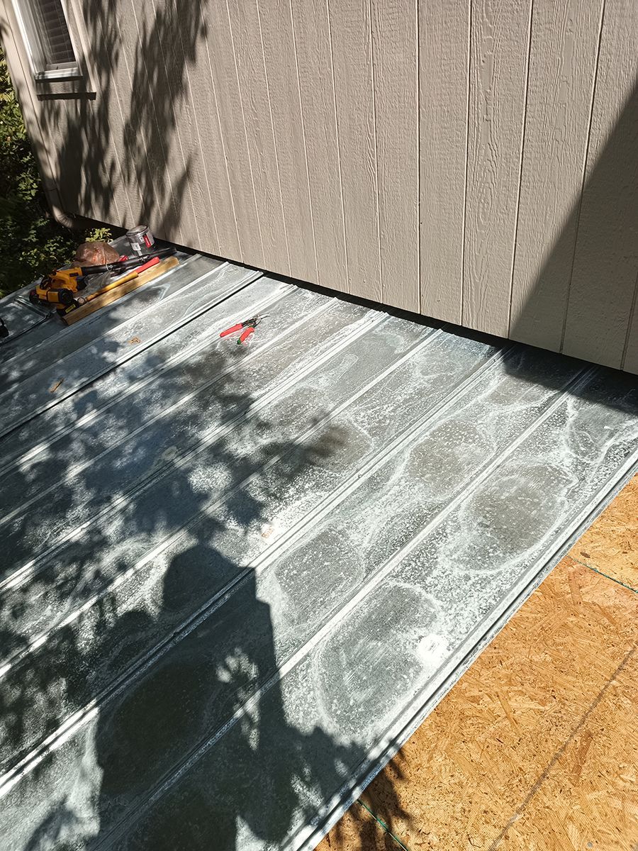 A shadow of a person is cast on a metal roof.