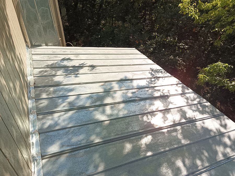 A close up of a metal roof with trees in the background.