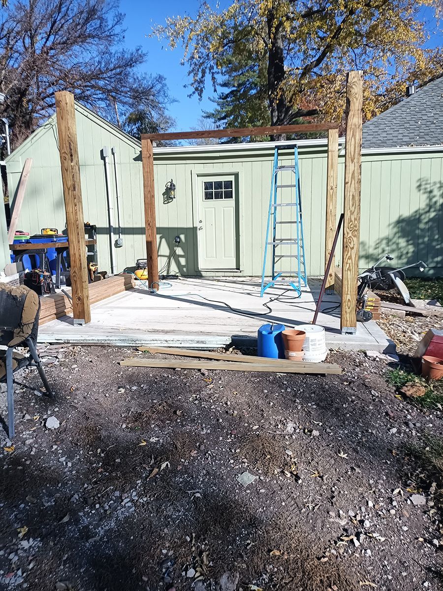 A wooden structure is being built in front of a green house.