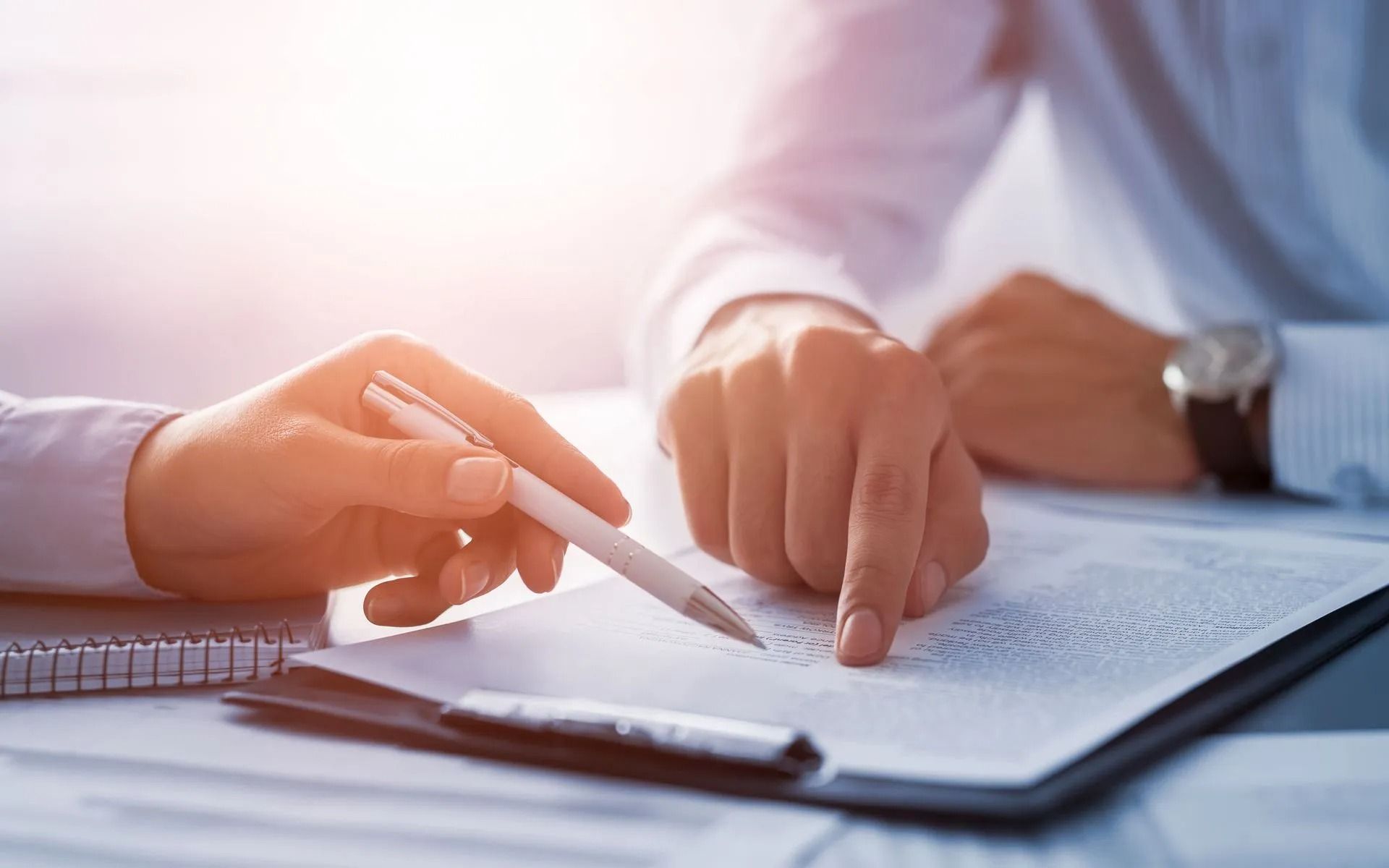 Two people reviewing a document, one pointing with a finger and the other holding a pen.