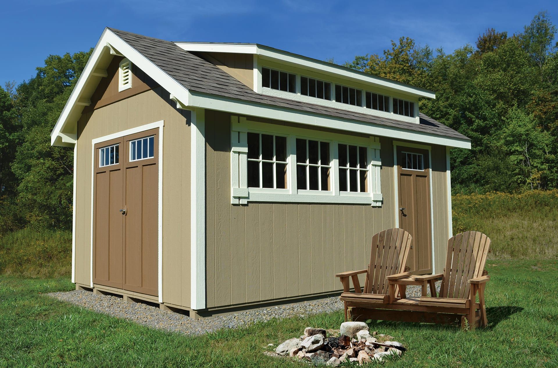 A shed with two chairs and a fire pit in front of it