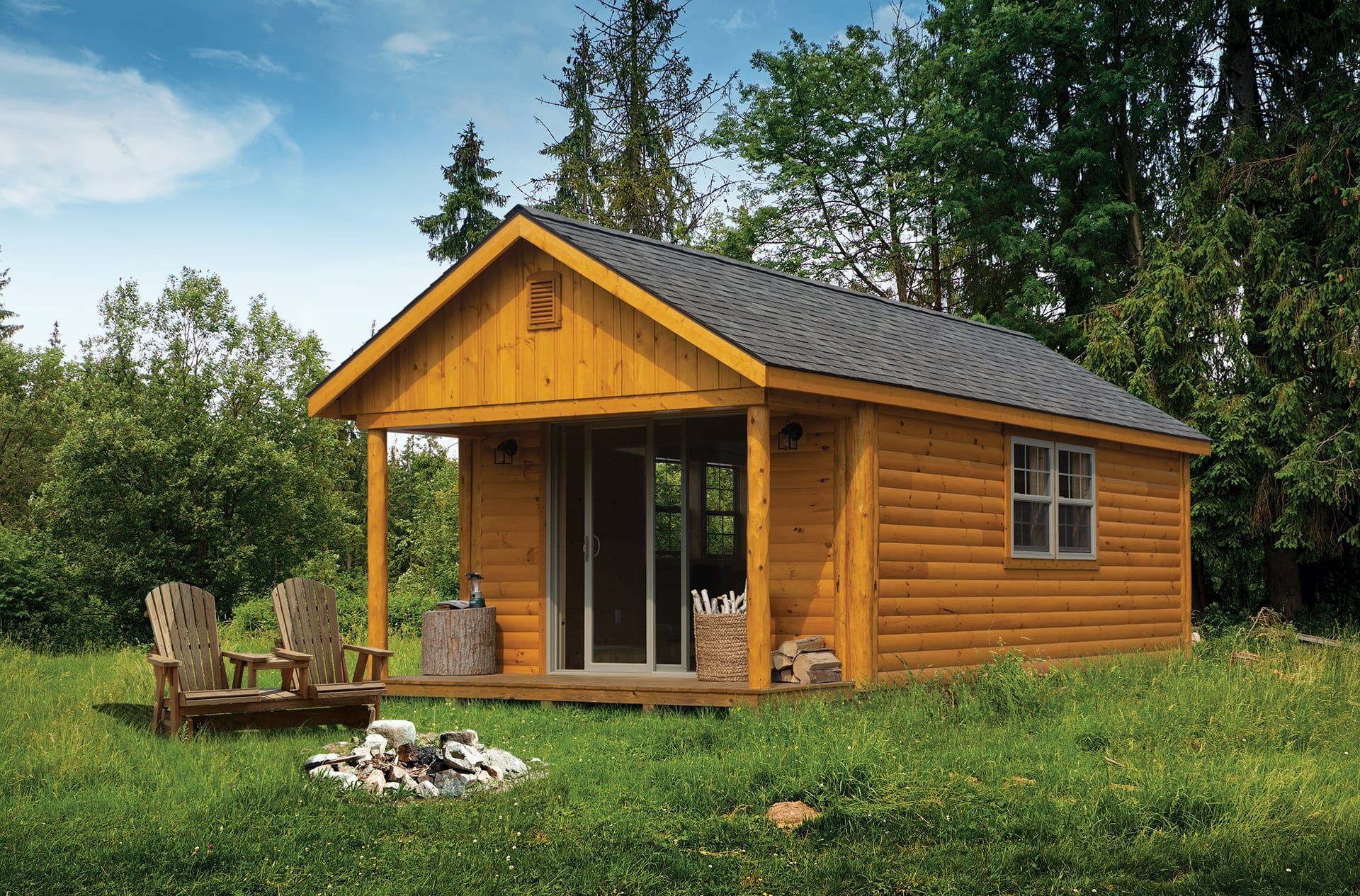 A small log cabin with a porch and chairs in the grass