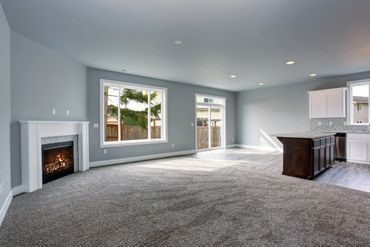 An empty living room with a fireplace and a large window.