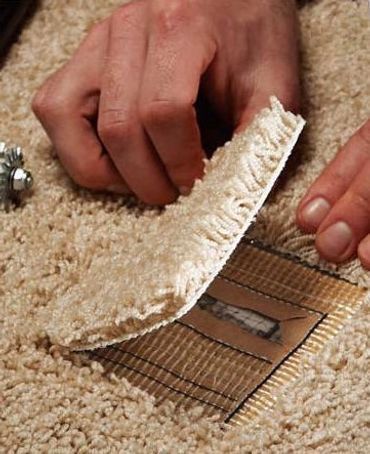 A person is cutting a piece of carpet with a pair of scissors