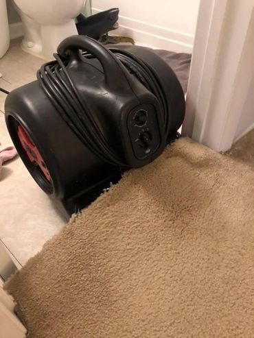 A vacuum cleaner is sitting on top of a carpet in a bathroom.