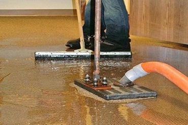 A person is using a mop to clean a flooded floor.