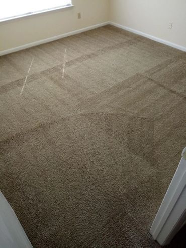 A bedroom with a large carpeted floor and a window.