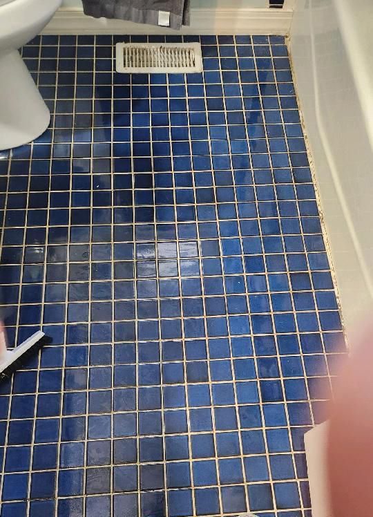 A blue tiled floor in a bathroom next to a toilet