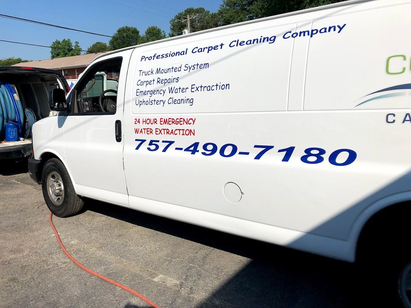 A white van for a carpet cleaning company is parked on the side of the road.