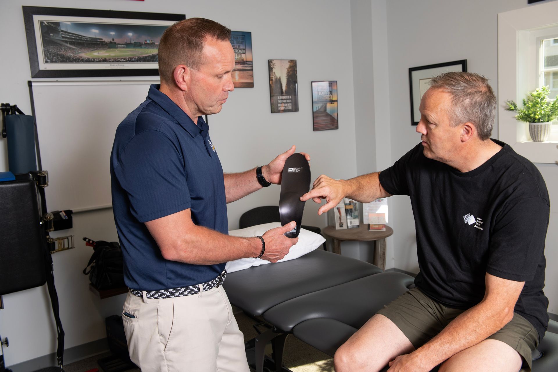 Mark Powicki showing his patient how custom orthotics will help his back and knee pain