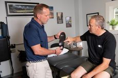 Mark Powicki showing his patient how custom orthotics will help his back and knee pain