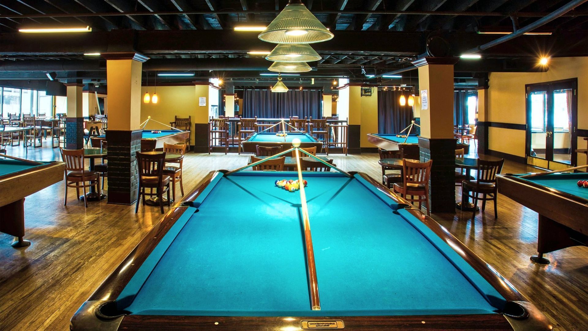 A pool table in a large room with tables and chairs